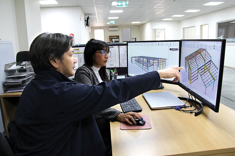 Engineers in the office discussing a design on the computer screen.